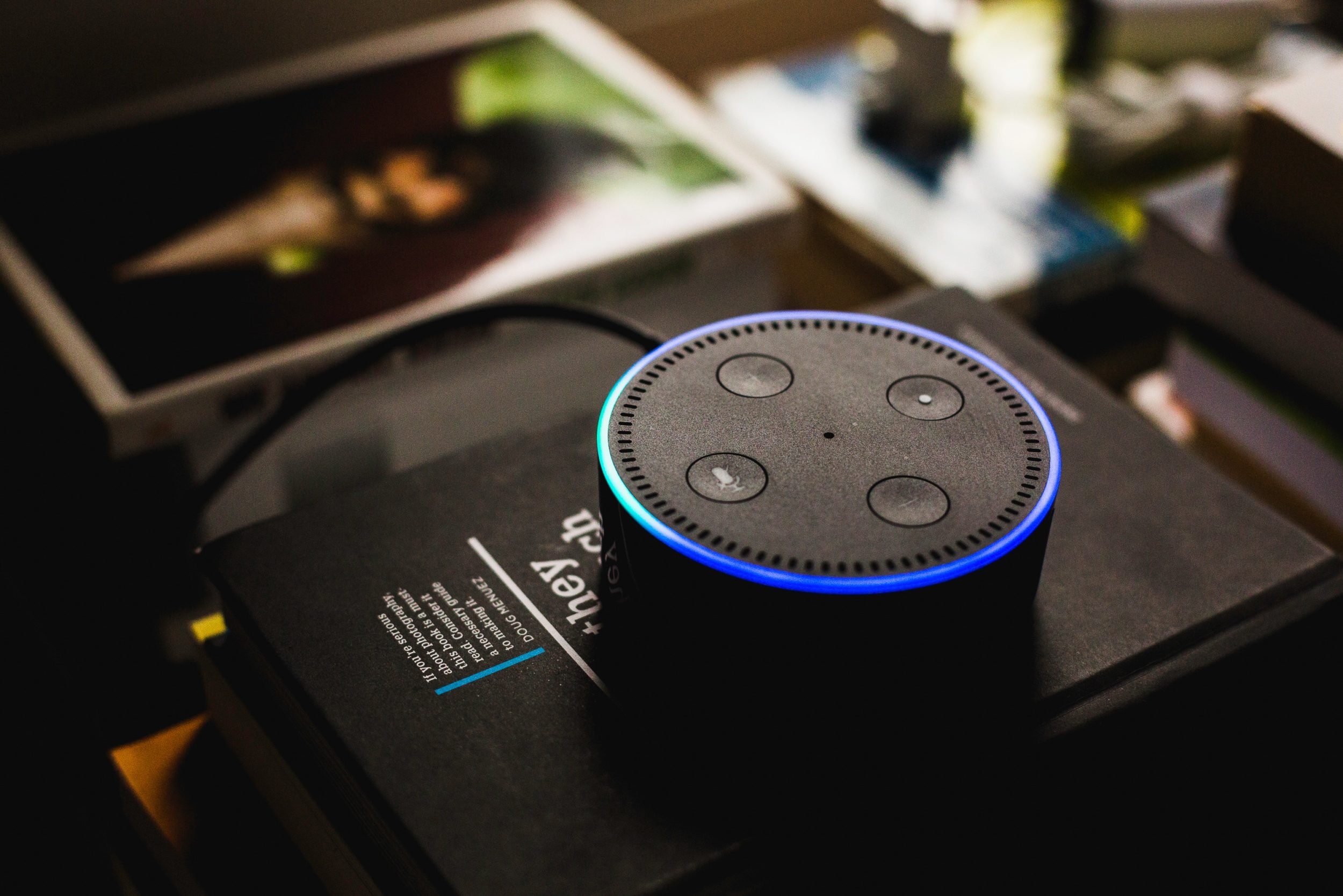 Amazon Dot with Alexa voice assistance sitting on top of books