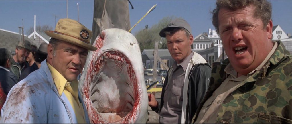 Men standing on a dock in front of shark.