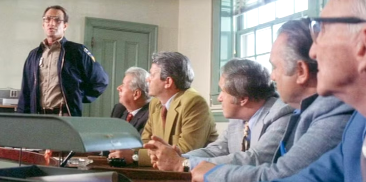 Man speaking to group of people in town hall.