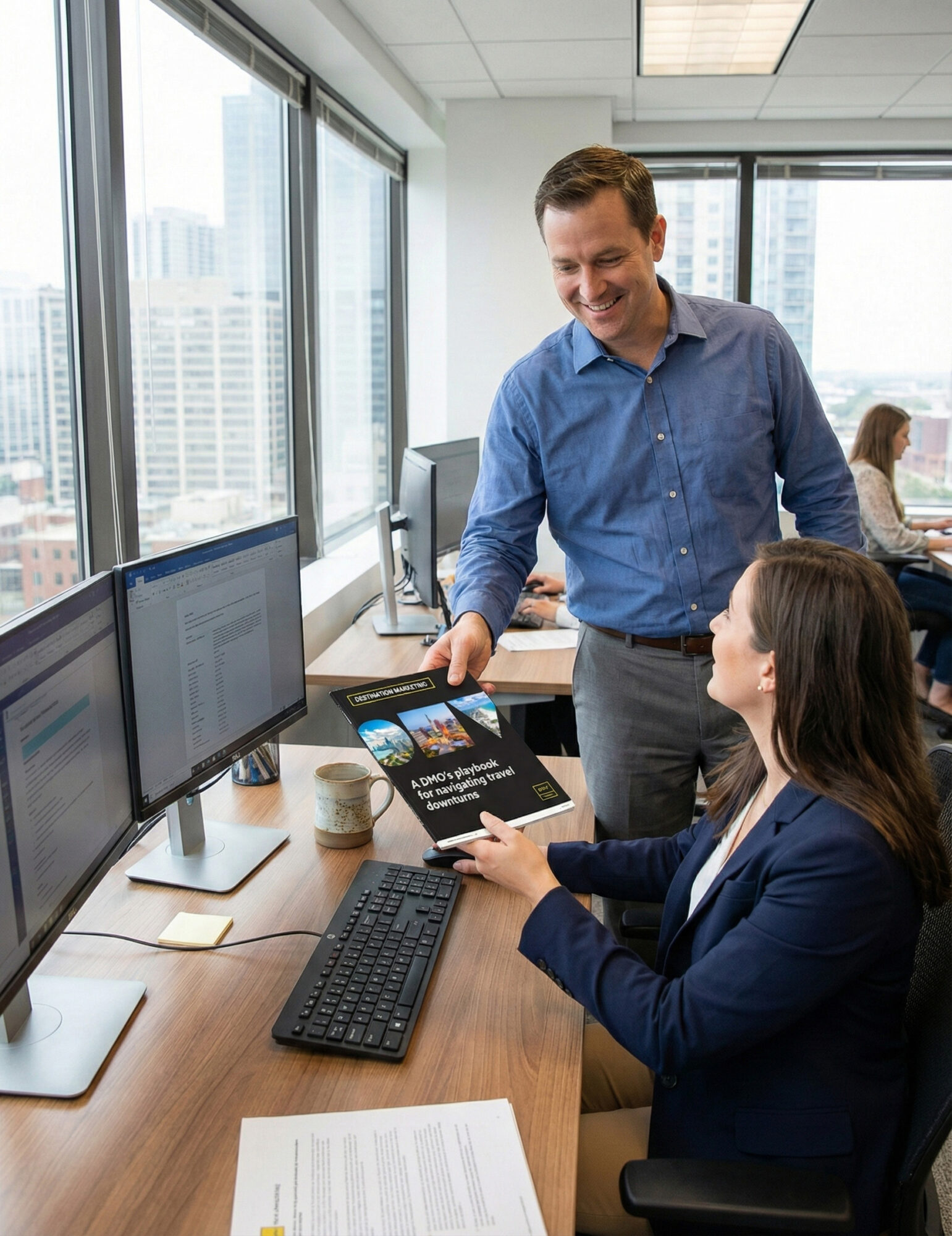 Man and woman at office sharing DMO playbook for navigating travel downturns, including the role of AI, social listening, and sentiment tracking in shaping campaigns, emerging trends like micro-trips, coolcations, and passion-driven travel, and a three-part strategic playbook to help DMOs prepare for 2026